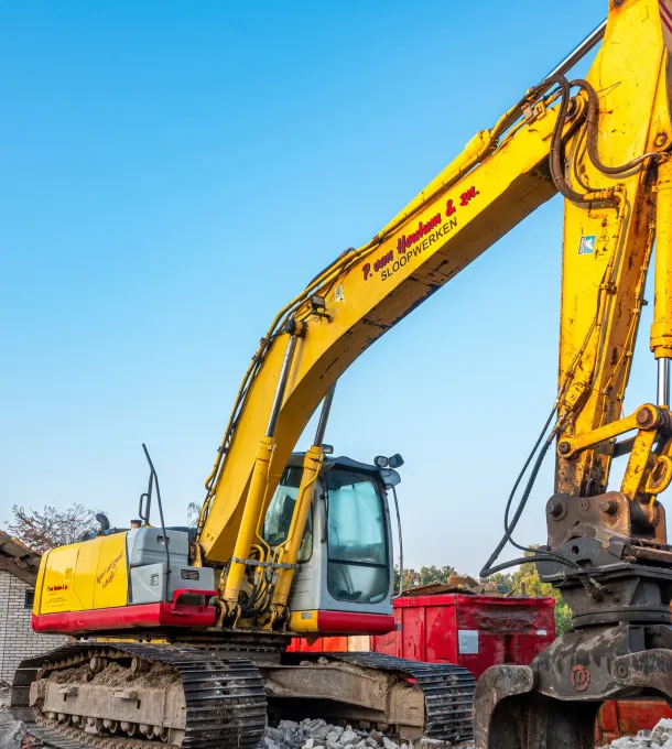 Yellow excavator working amid rubble at a demolition site
