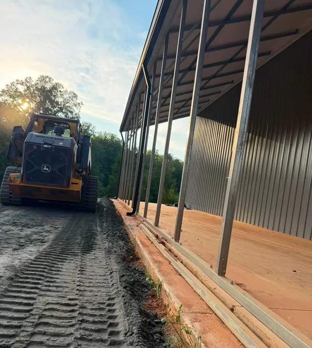 Dozer grading the ground beside a metal-roof building