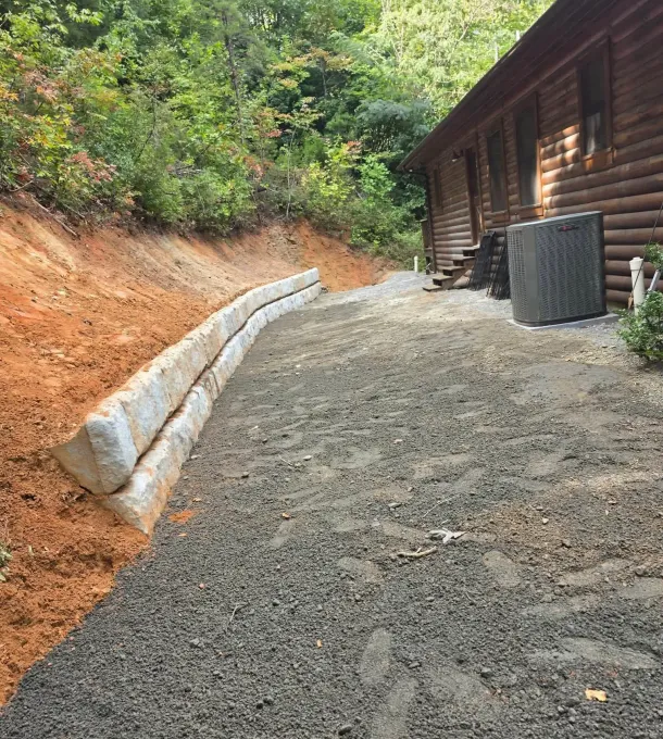 Block retaining wall and gravel drive beside a log cabin