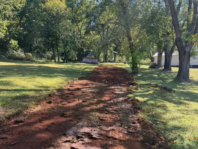 Red-clay trail graded through a wooded lot