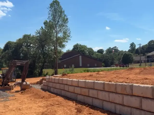 Block retaining wall under construction with drain pipe on a graded site