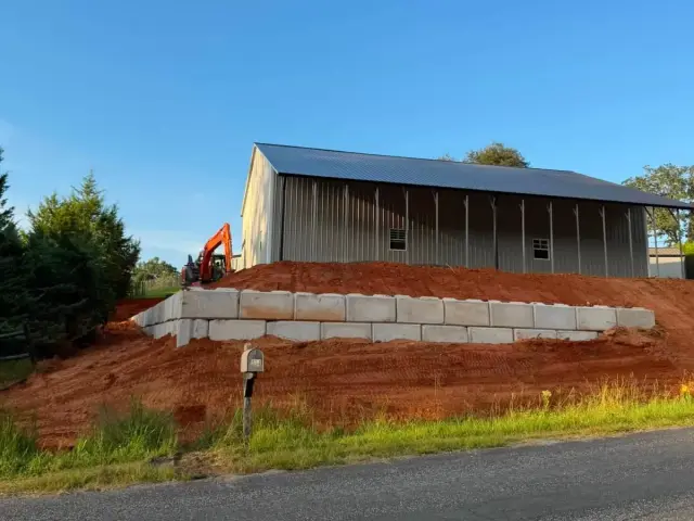 Block retaining wall below a building beside the road
