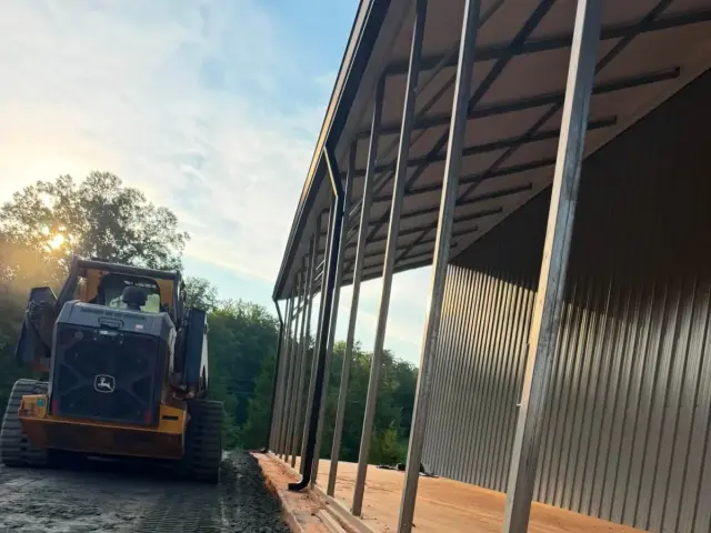 Dozer grading beside a metal-roof building