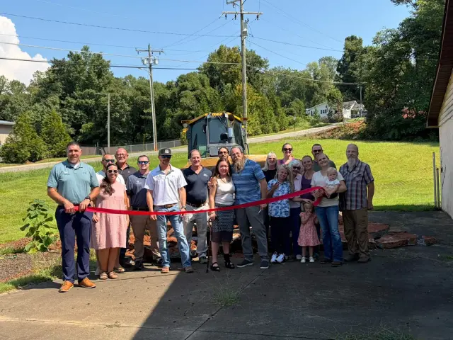 Ribbon cutting at the mini golf groundbreaking, H&L dozer behind the crowd