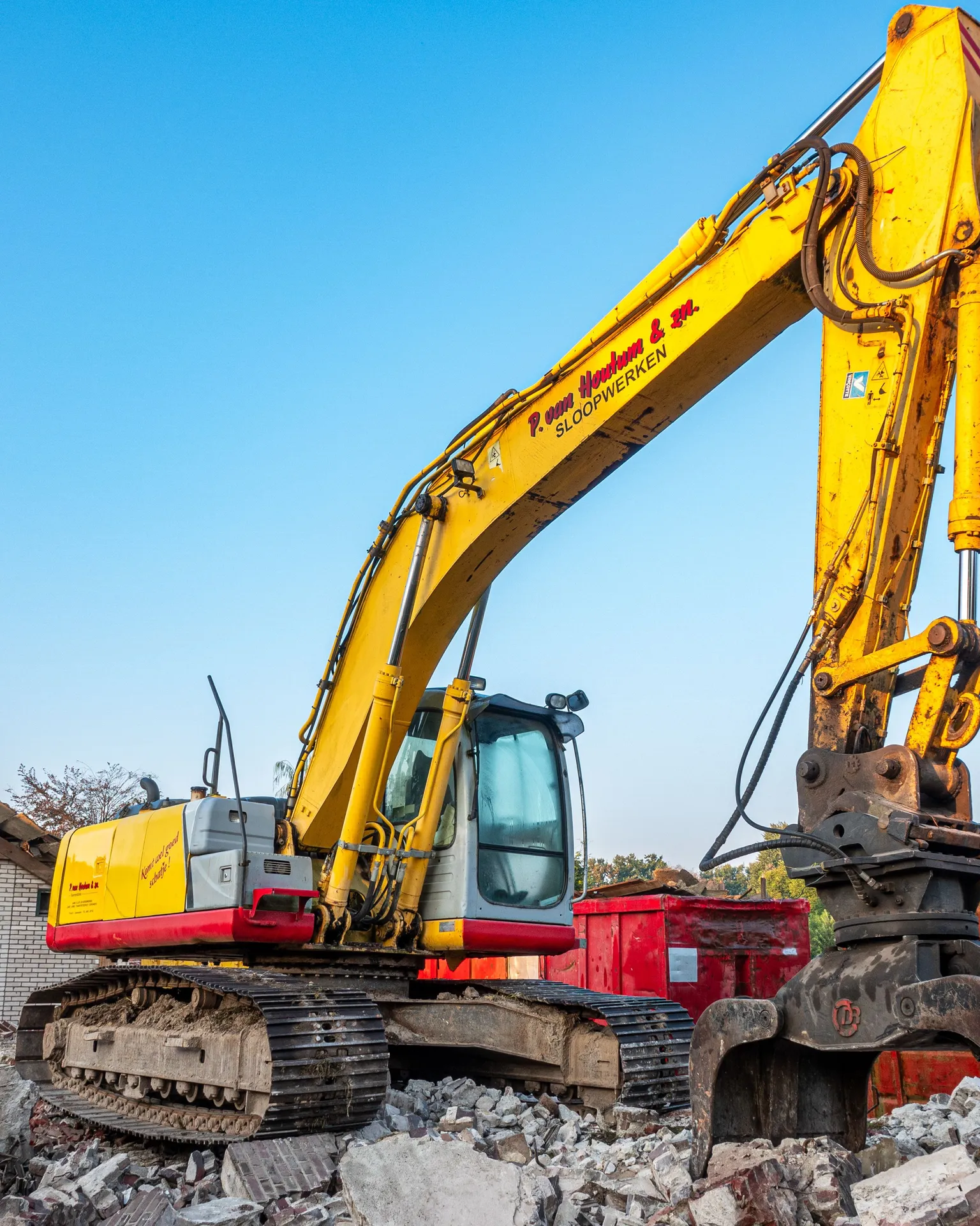 Yellow excavator working amid rubble at a demolition site