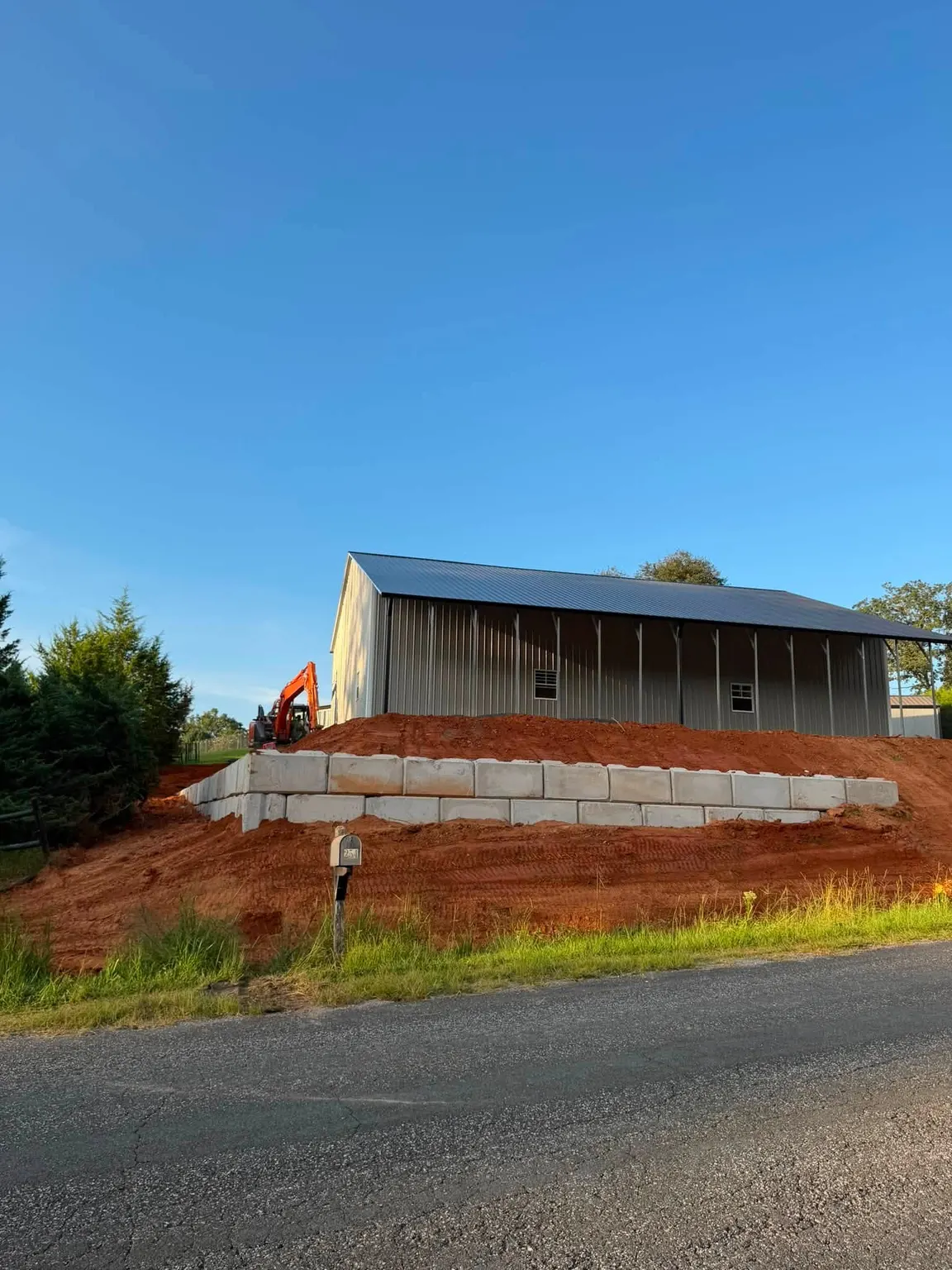 Block retaining wall and graded bank below a building beside the road