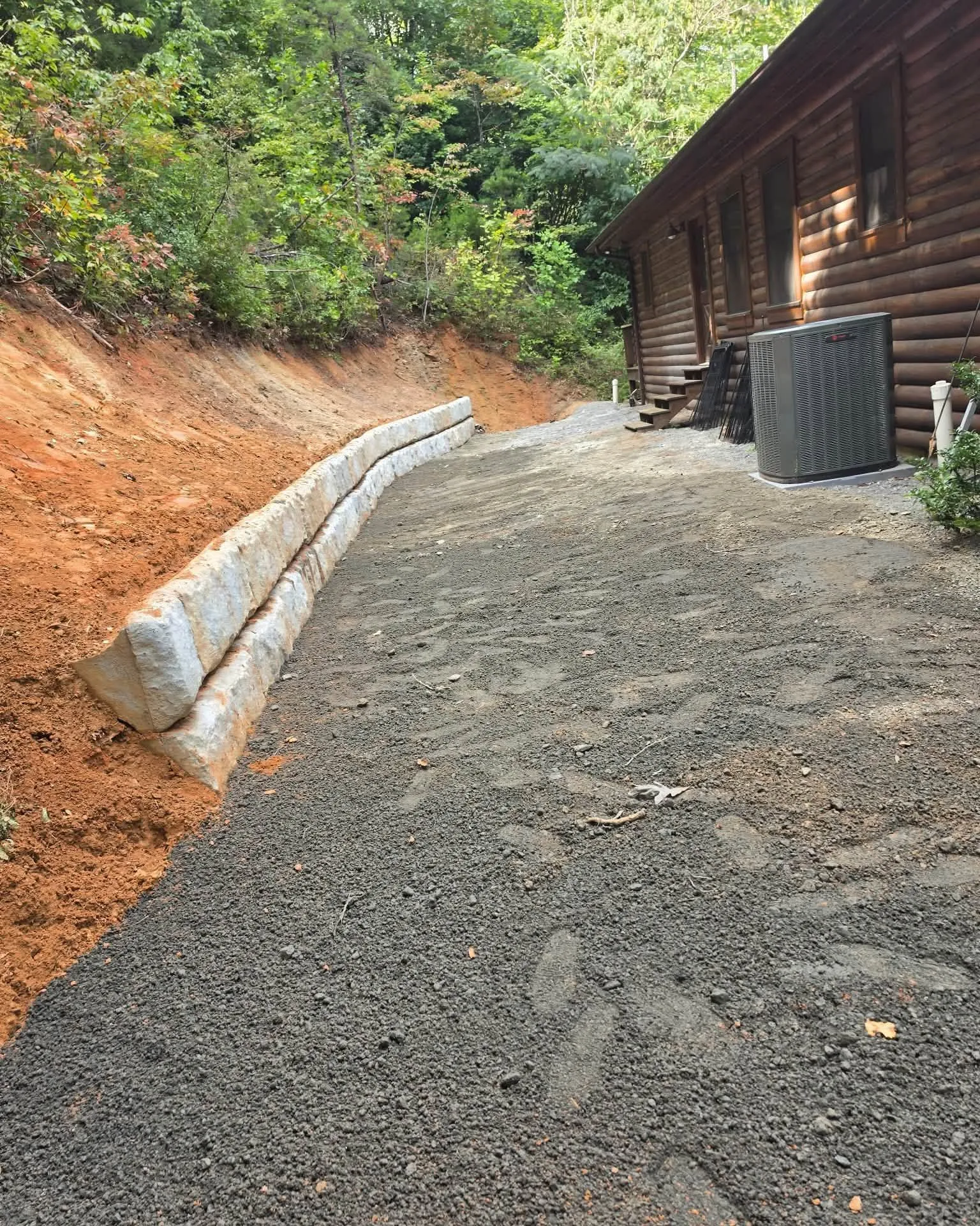 Block retaining wall and gravel drive beside a log cabin