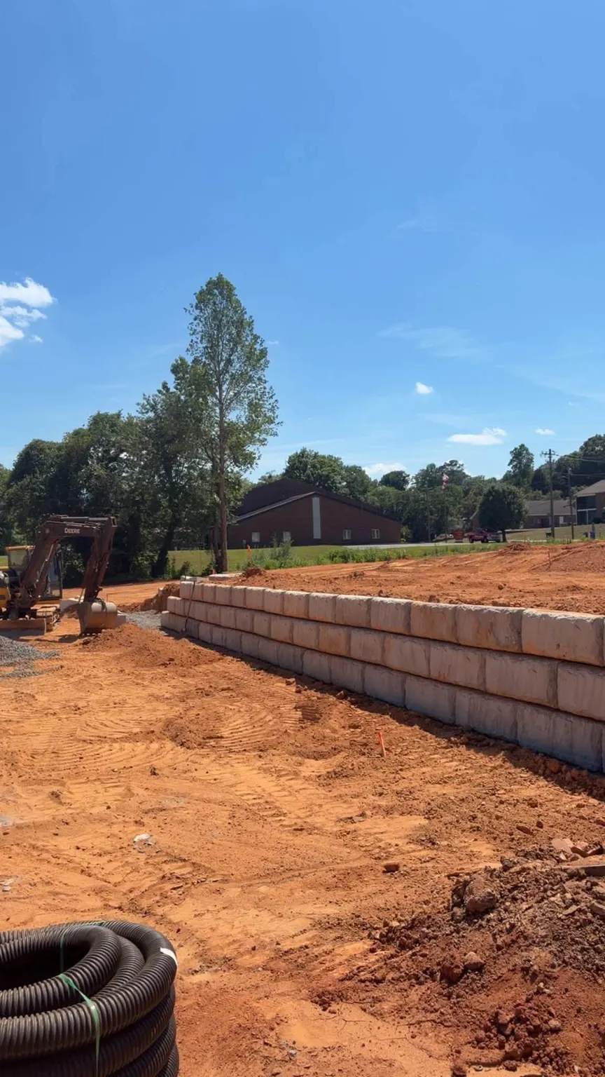Block retaining wall going up on a graded site, drain pipe ready