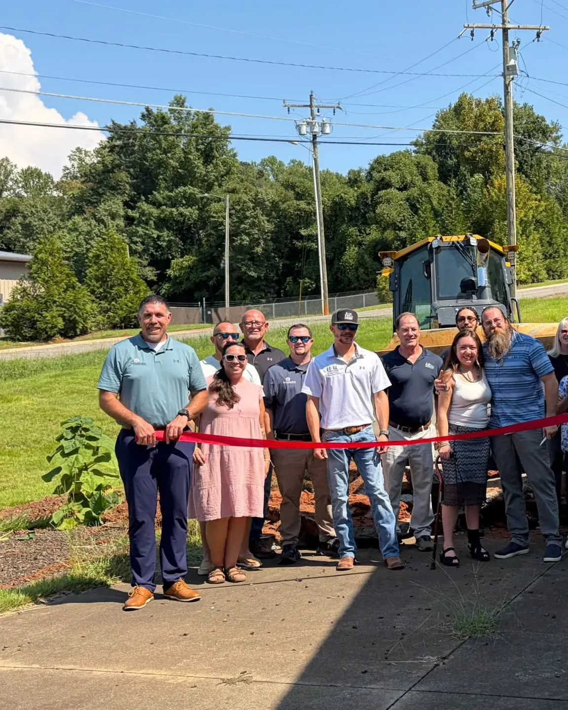 Ribbon cutting at the Foothills Mini Golf ground breaking in Rutherfordton, with an H&L dozer behind