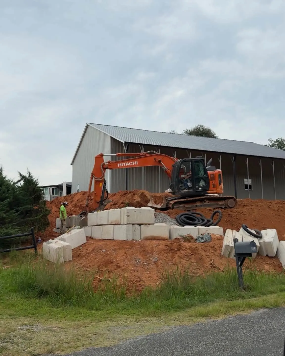 Excavator setting retaining wall blocks beside a building